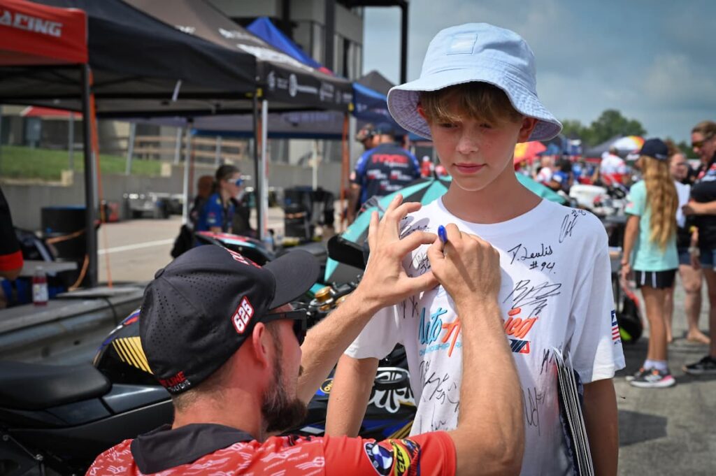 a motorcycle racer singing a fan's t-shirt