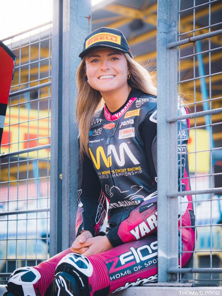 woman motorcycle racer sitting by the pit fence