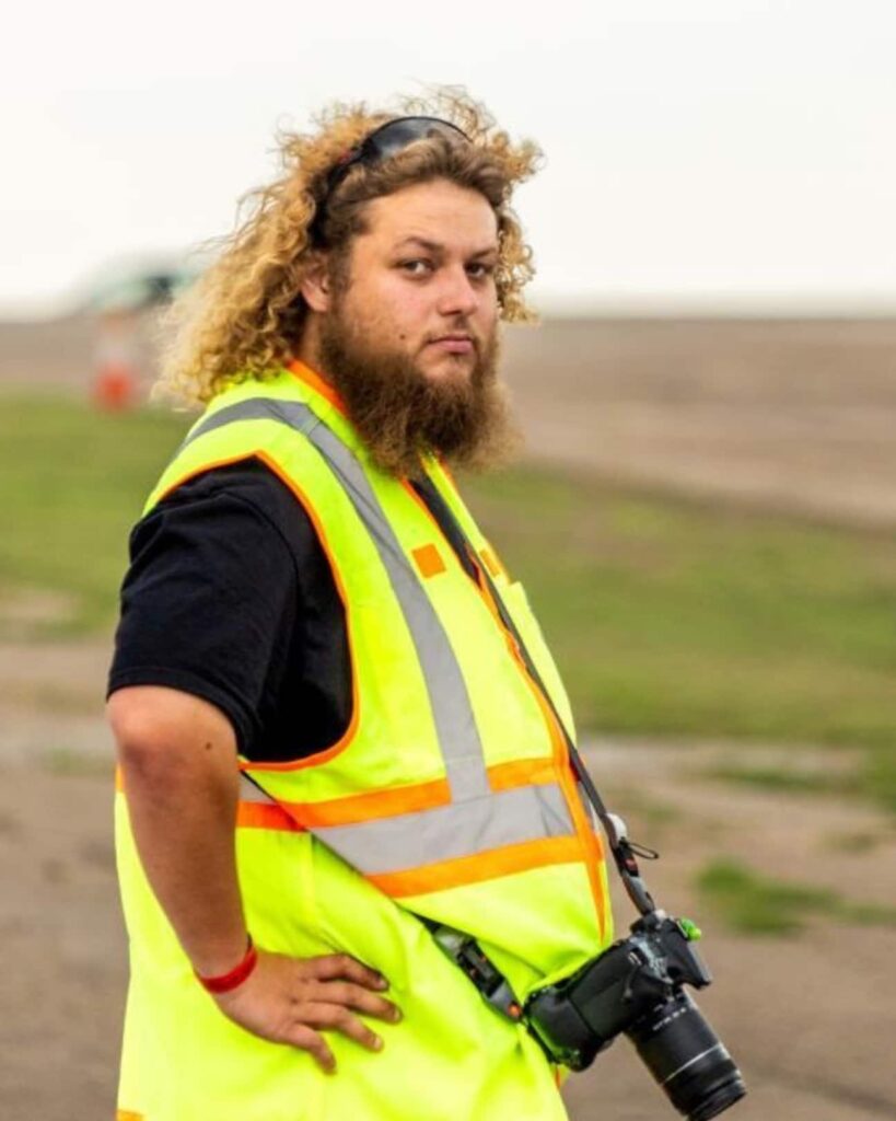 a photographer standing in an open field with his camera