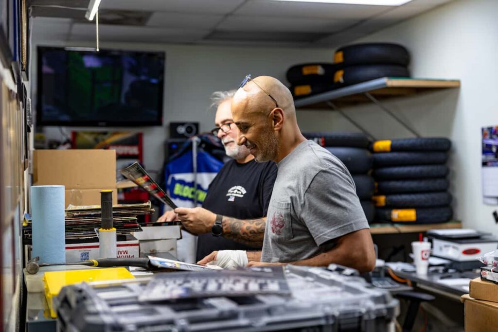 two man standing next to each other and looking at magazines