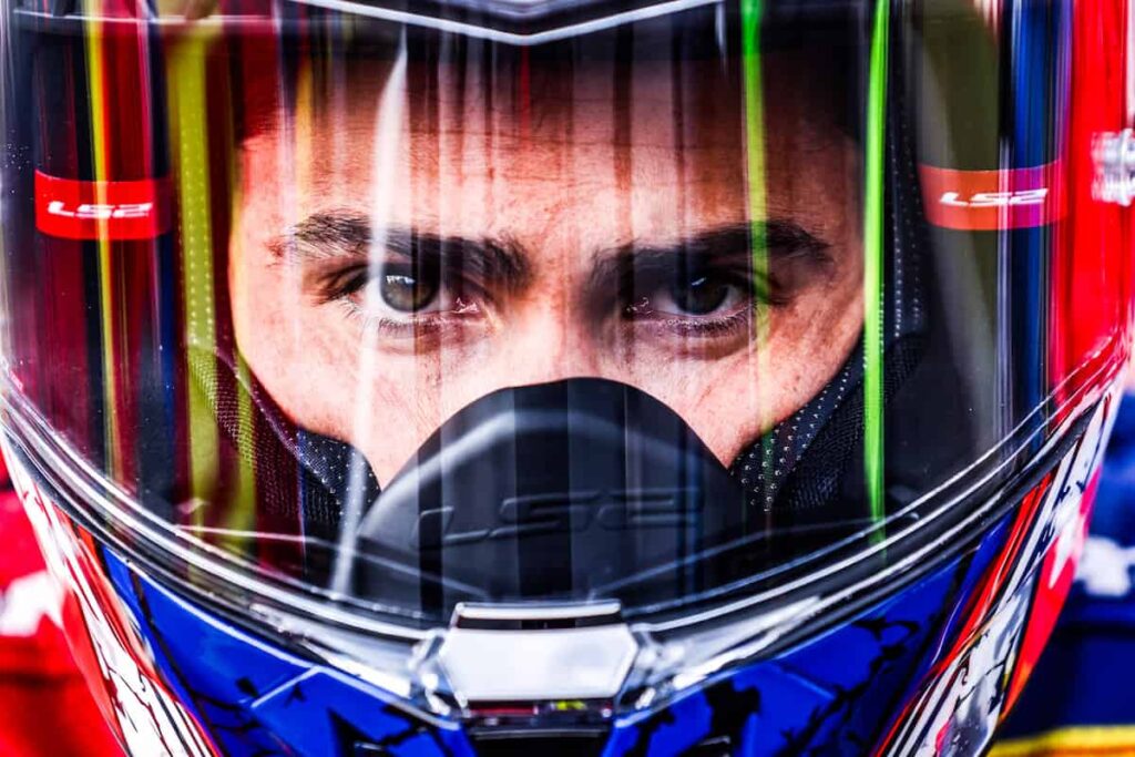 a motorcycle racer in his helmet looking at the camera