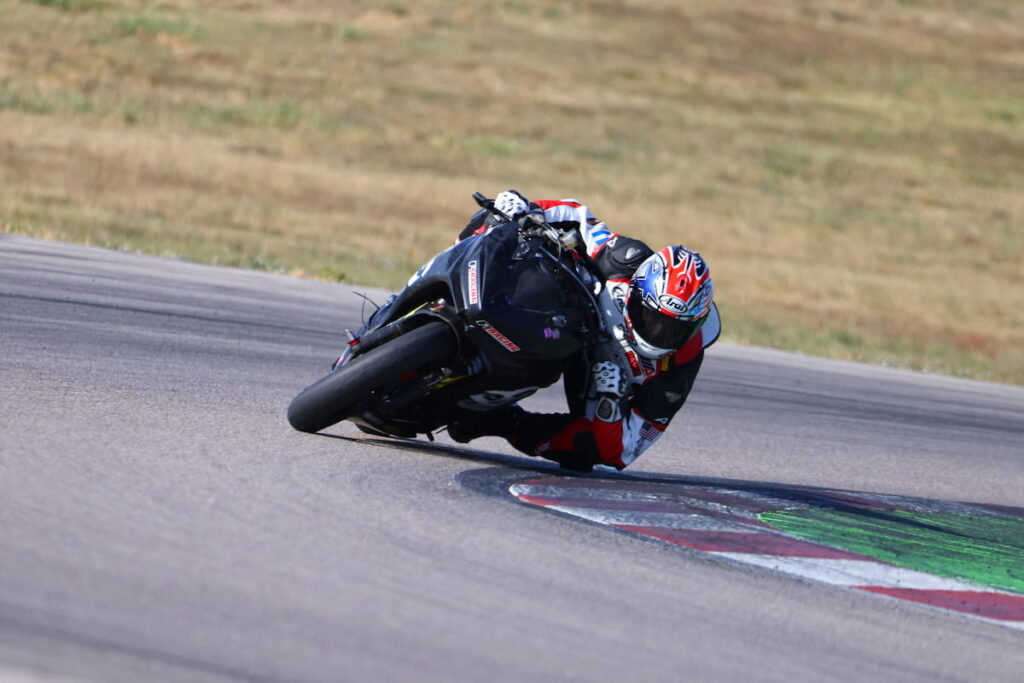 a motorcycle racer leaned at the apex with knee and elbow almost dragging