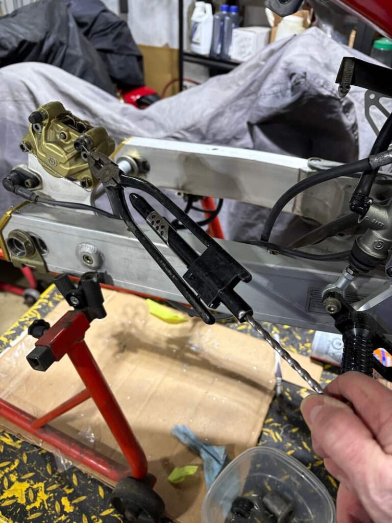 Motorcycle brake caliper is being safety wired by plier