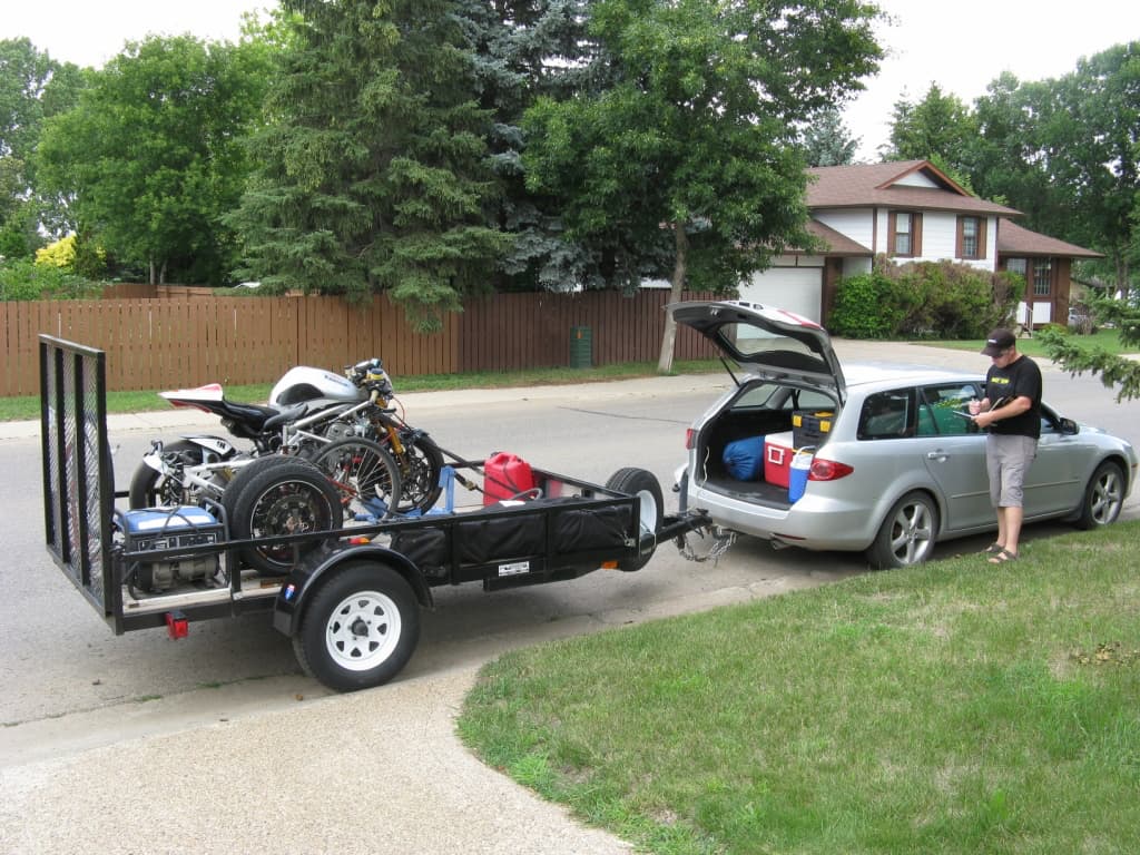 a man next to the van with motorcycle trailer checking the checklist
